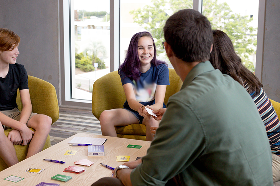 A family smiling and having fun playing the Interesting Conversations game.