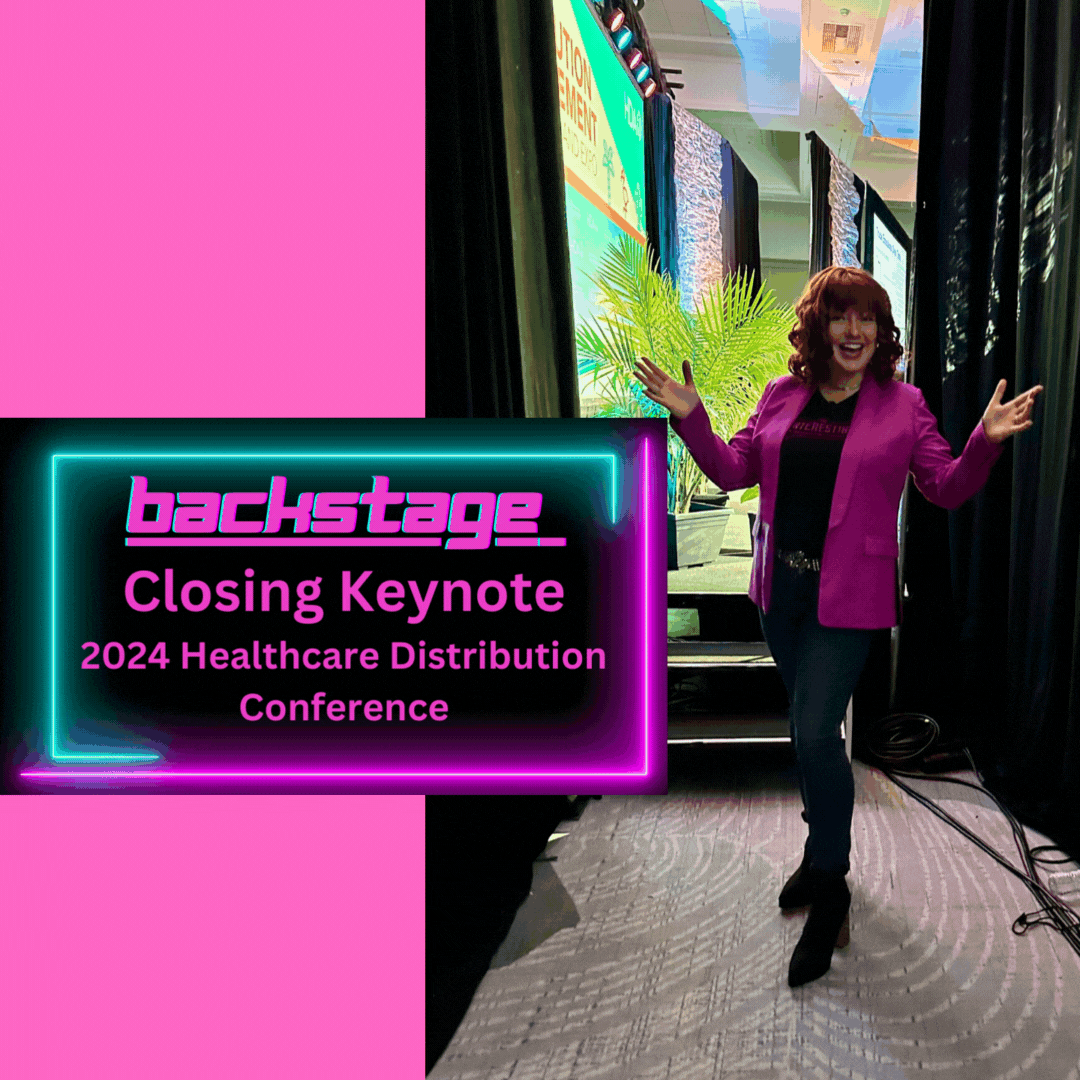 "Professional keynote speaker Deedre Daniel, a mid-forties white woman with red curly hair, wearing a pink jacket with a striking black stripe, a black tee with The Interesting Conversations Company logo in sparkly pink glitter, fitted jeans, and black ankle boots with sequined heels. She stands backstage at the 2024 Healthcare Distribution Conference, smiling and posing joyously as she prepares to address a large audience with her talk: "PEANUT BUTTER BREAKOUT: ESCAPING THE STICKY RUT AND EMBRACING YOUR INTERESTING TRANSFORMATION IN A JIFF!"